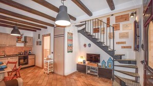 A cozy kitchen with wooden cabinets, a dining area with a red chair, and a staircase with wooden steps and metal railings. - 2 bedroom lovely home in Ragusa RG (Ragusa RG)