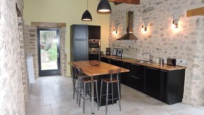Una cocina moderna con una mesa de comedor de madera, armarios negros y paredes de piedra.