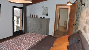 Slaapkamer met een kamerbreed tapijt, een bed met oranje beddengoed, een grijze inloopkast en een houten plafond.