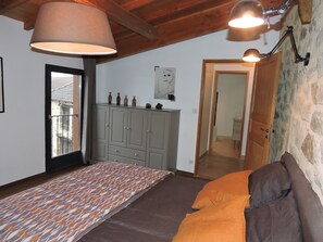 A bedroom with a patterned rug, a bed with orange bedding, a grey wardrobe, and a wooden ceiling.