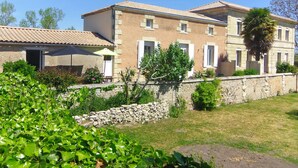 Un bâtiment à deux étages, doté d’une façade en pierre, de nombreuses fenêtres avec volets et d’un toit recouvert de tuiles.