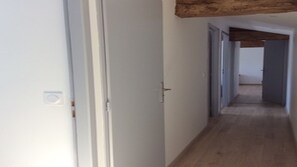 Een gang met houten vloer en witte wanden.
