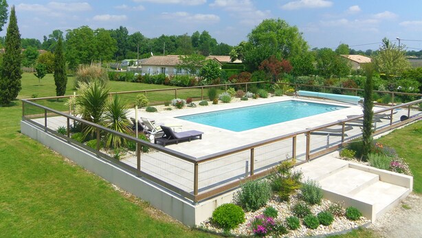 Une piscine rectangulaire, dotée d’une plage carrelée et entourée d’une clôture en métal.