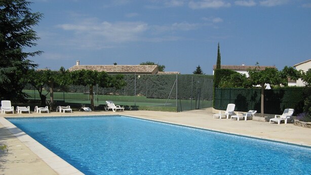 A rectangular swimming pool with clear blue water, surrounded by white lounge chairs and a fenced area with greenery. - 400m to the center of Uzès, appartment for 4 people (Uzès)