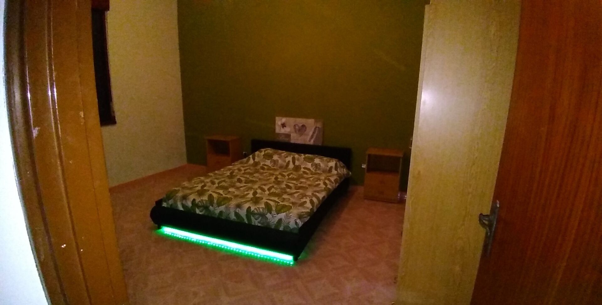 Une chambre à coucher avec un lit, des murs verts et une porte.