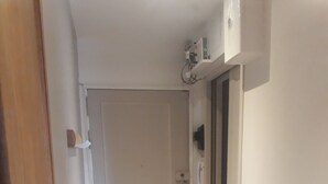 Ein Korridor mit Holzboden, einer geschlossenen Tür und einem an der Wand montierten Stromkasten.