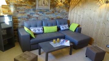 Un salon moderne avec un canapé d’angle, des poufs et une table basse.