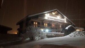 Een gebouw bedekt met sneeuw bij nacht, met verlichte ramen en een houten gevel.