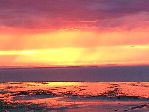A sunset over a body of water with a distant shoreline.