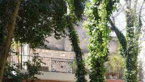 A modern building with a glass entrance, surrounded by greenery and a gravel path.