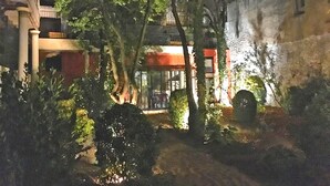 A courtyard with trees and a building with a red awning.