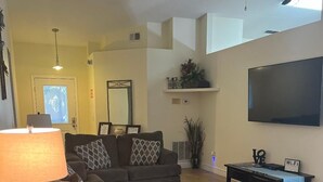 Een woonkamer met een bank, een salontafel, een televisie en een plafondventilator.