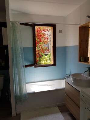 A bathroom with a bathtub, a window with a view of a tree, and a sink. - Air-conditioned house with sea view, 80 metres from the beach (Lumio)