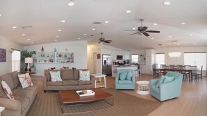 A spacious living room with a sofa, armchairs, a coffee table, and a dining area with a table and chairs. - Beachfront Condo With Panoramic Views of the Gulf Plus Beach Gear, Grill & Wifi (Indian Rocks Beach)