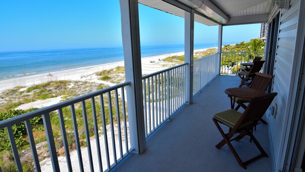 A covered balcony with a view of the beach and ocean. - Beachfront Condo With Panoramic Views of the Gulf Plus Beach Gear, Grill & Wifi (Indian Rocks Beach)