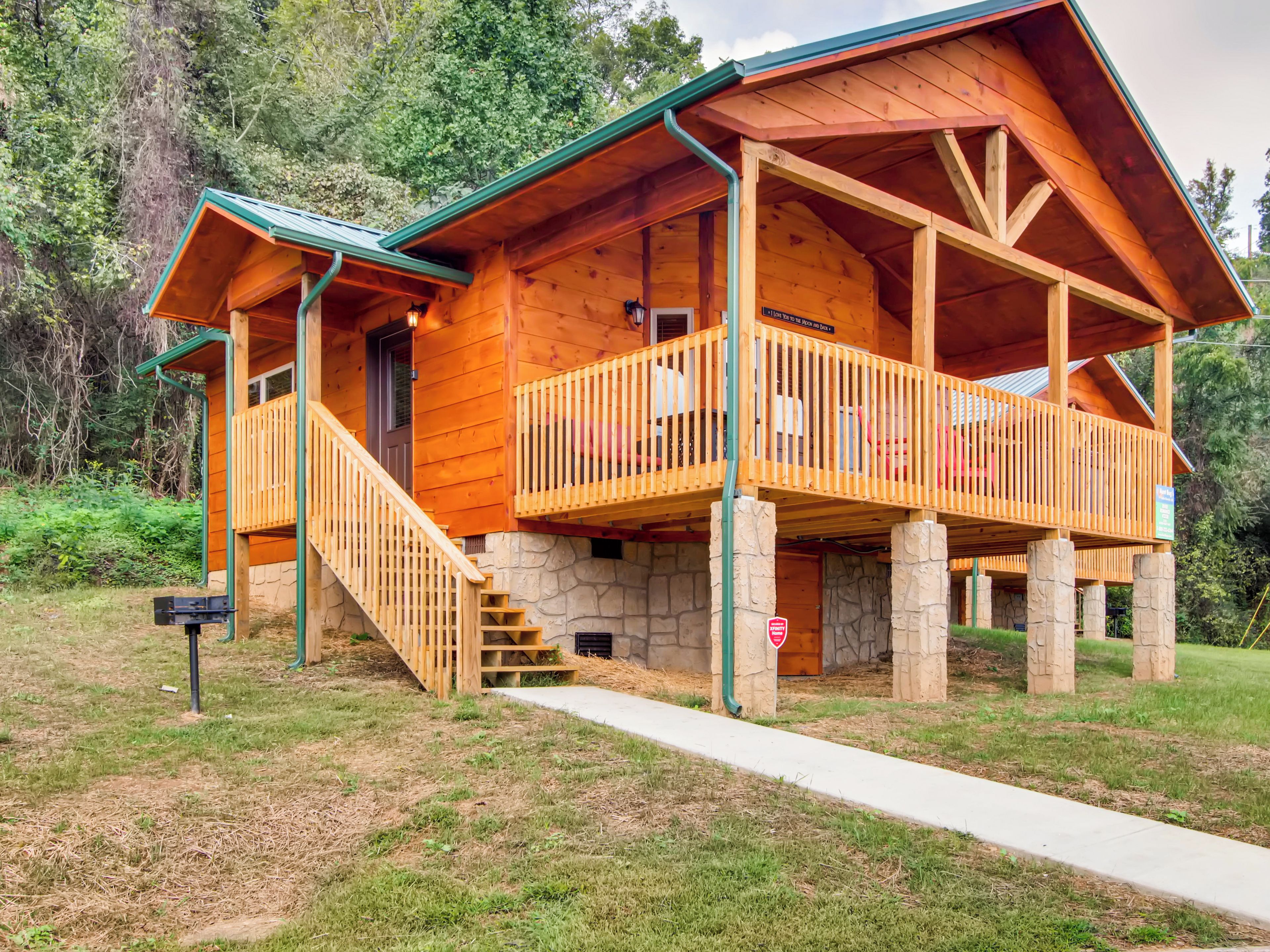 A wooden cabin with a stone foundation, a porch, and a staircase leading to the entrance.