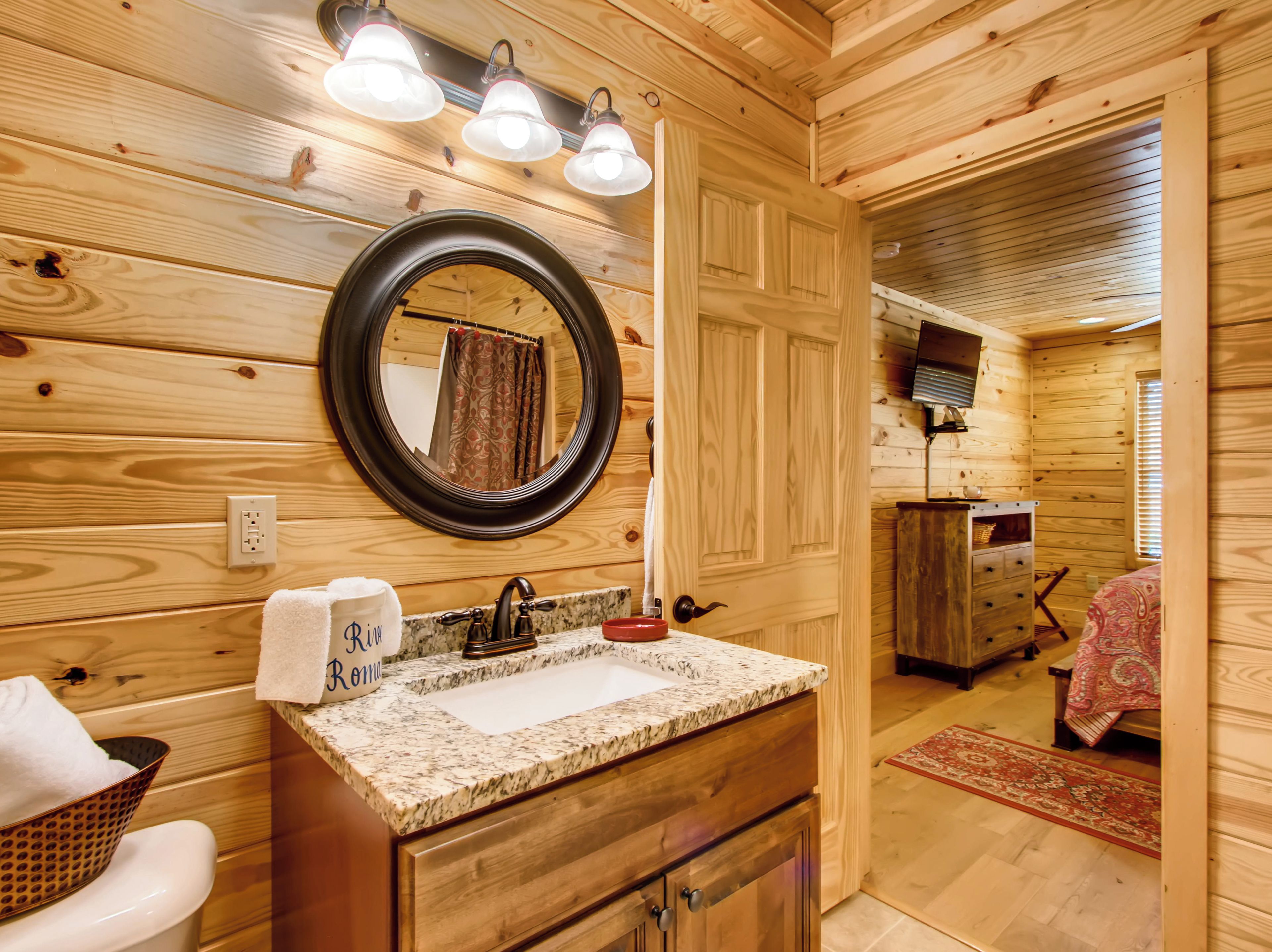 Ein Badezimmer in einer Holzhütte mit Waschbecken, Spiegel und Holzausbau.