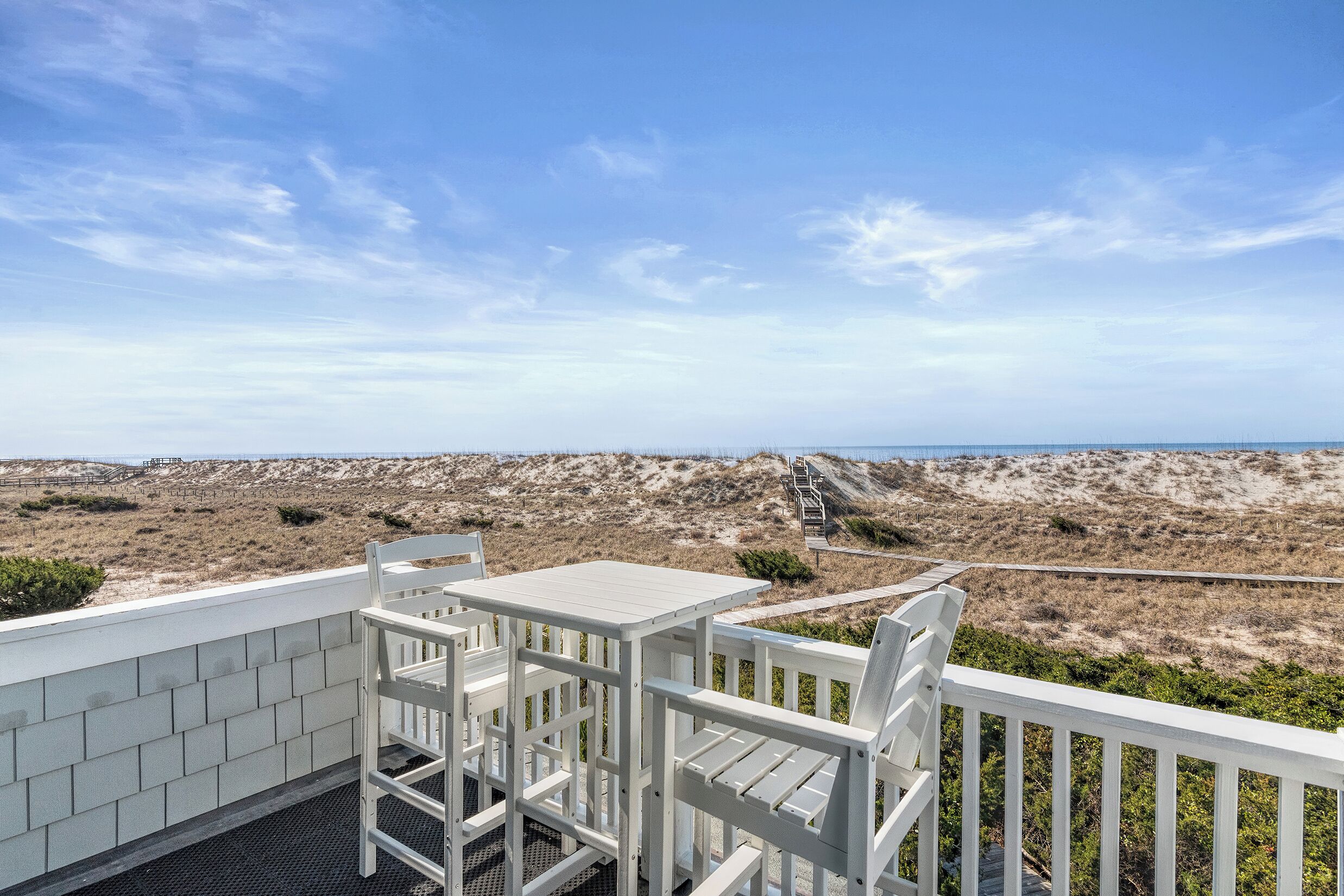 Área de estar ao ar livre com vista para a praia e dunas.