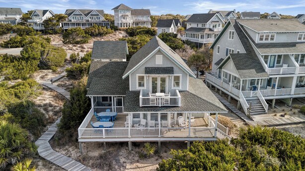 A coastal house with a deck, multiple windows, and a surrounding landscape. - Welcome to BIS BALD!, your Oceanfront Escape on BHI! (Bald Head Island)