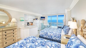 A hotel room with two beds, a kitchenette, a balcony with a view of the ocean, and a large mirror. - Oceanfront Retreat- Poolside View- Budget Friendly (Daytona Beach)