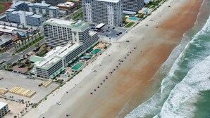 An aerial view of a beachside hotel with multiple buildings, a sandy beach, and a pool area. - Oceanfront Retreat- Poolside View- Budget Friendly (Daytona Beach)