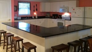 A kitchen with a large island, white cabinets, and wooden stools. - This is it! Spacious Luxury 8 Bedroom Villa, Pool, Hs Internet (North Myrtle Beach)