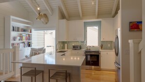 Una cucina moderna con isola centrale, elettrodomestici integrati e una libreria.