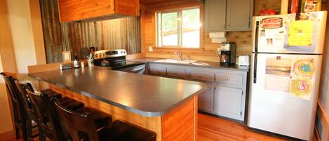 A kitchen with a central island, wooden cabinets, a refrigerator with magnets, and a window providing natural light.