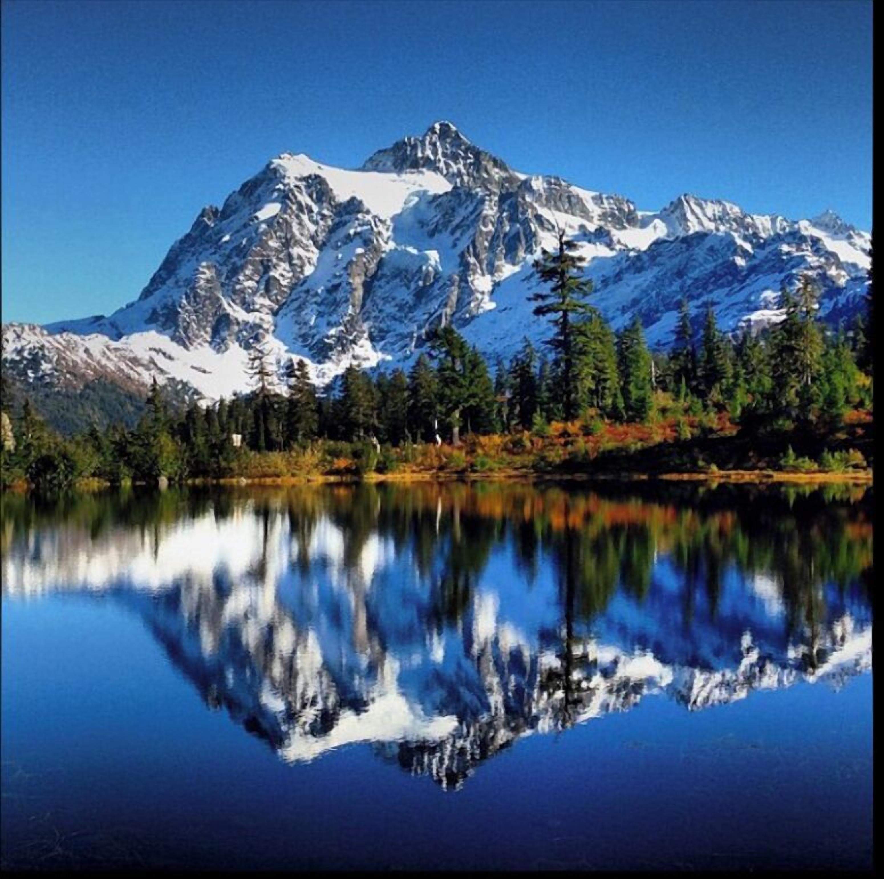 Una montaña reflejada en un lago tranquilo, con árboles y picos nevados.