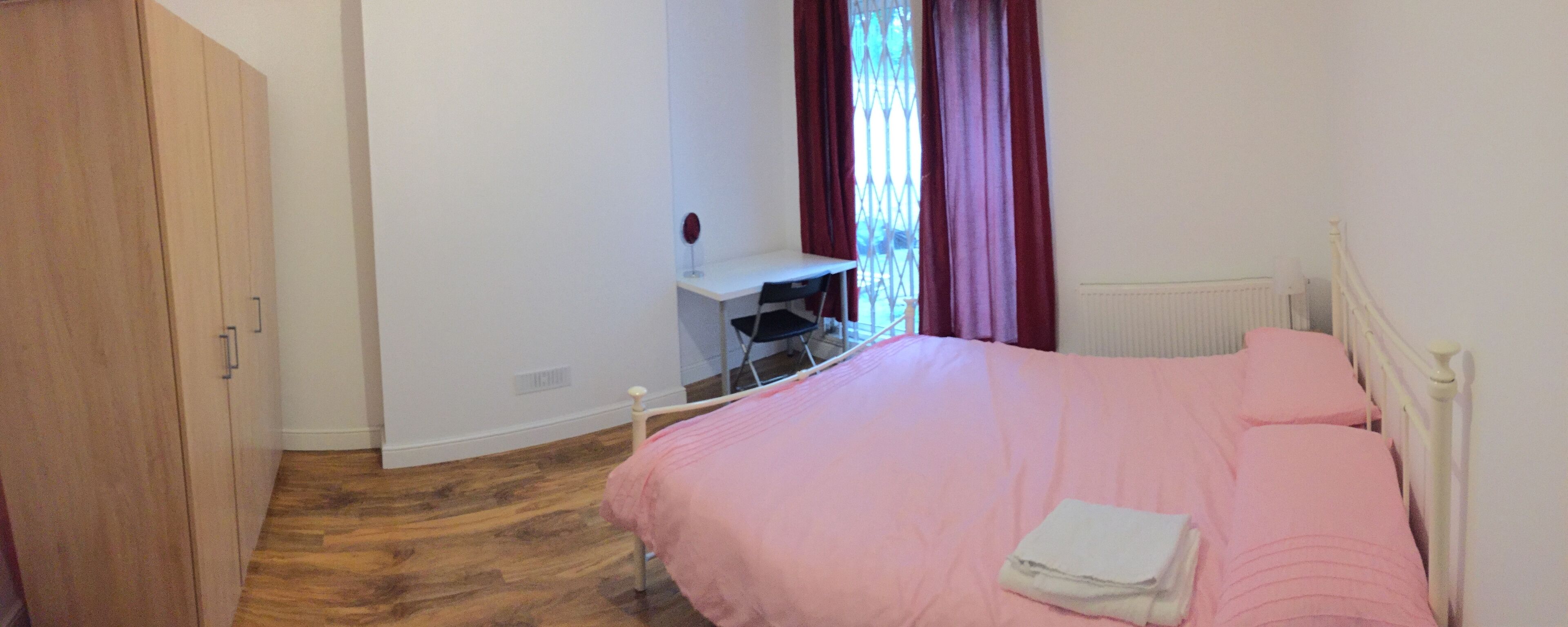 A bedroom with a bed, a desk, and a wardrobe.