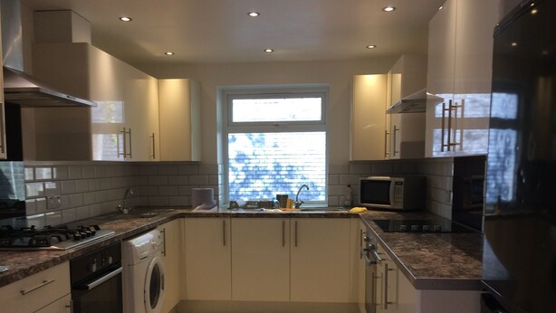 A modern kitchen with a built-in washer and dryer, a microwave, and a large window providing natural light. - The White House 7 DOUBLE BED HOUSE FULLY-EQUIPPED (London)