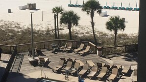 A beach view with a pool area, lounge chairs, and palm trees. - Beach, Sand, Shells, And An Ocean As Far As You Can See At Our Cozy Condo in PCB (Panama City)