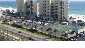 A hotel with multiple floors, a parking lot, and a view of the beach. - Beach, Sand, Shells, And An Ocean As Far As You Can See At Our Cozy Condo in PCB (Panama City)