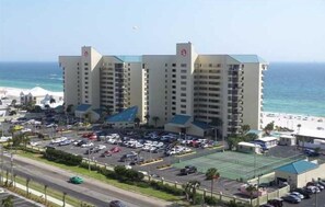 A hotel with multiple floors, a parking lot, and a view of the beach.