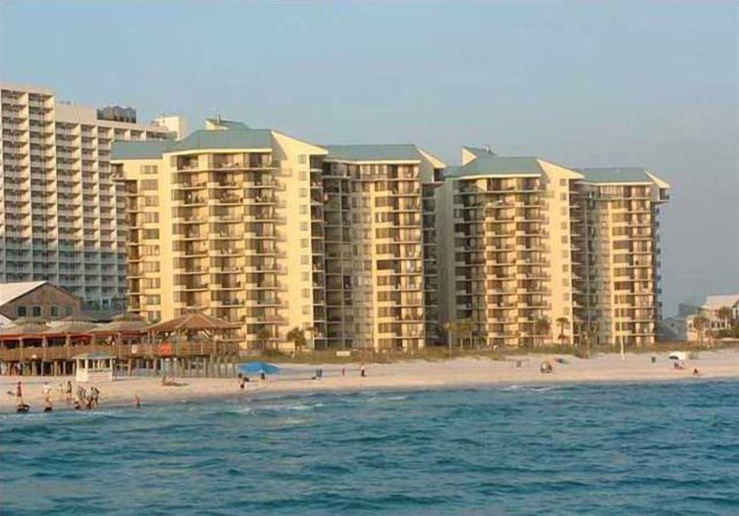 Ein Hotel direkt am Strand mit mehreren Hochhäusern, einem Sandstrand und dem Meer.