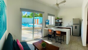 Cocina moderna con refrigerador, microondas y dispensador de agua. Posee una puerta corrediza de vidrio que da a una zona de piscina.