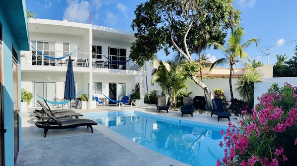 A modern hotel with a pool, outdoor seating, and lush landscaping. - AQUA GUESTHOUSE 1~ STEPS FROM BEACH ~ A+ INTERNET (Puerto Morelos)