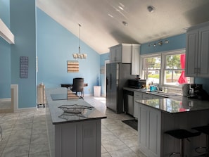 Een moderne keuken met een centraal eiland, roestvrijstalen apparatuur en uitzicht op de omgeving.