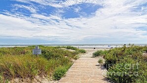 Pasarela de madera que lleva a una playa con un cartel.