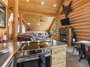 Interior de uma cabana de tronco com cozinha, sala de jantar e sala de estar.