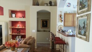 A living room with a sofa, a coffee table with a vase, a kitchen area with a counter and bar stools, and a dining area with a table and chairs. - Golf ... Bird Watching, Biking, Hiking, Sunsets, Star Gazing ... Oh, great Golf (Green Valley)