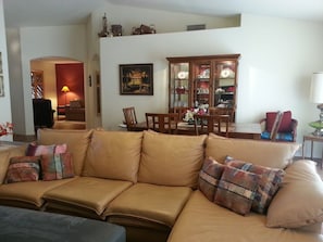 A living room with a beige sofa, a dining table, and a cabinet with glass doors.