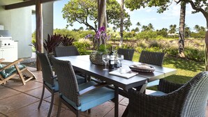 An outdoor dining area with wicker chairs and a table set for two, overlooking a lush garden with tropical plants and trees. - Views, Views, Views Chef's Kitchen, Ample Supplies, Home Office, Weekly Discount (Kamuela)
