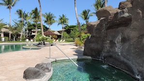 A clear pool with a rock formation, palm trees, and a building in the background. - Views, Views, Views Chef's Kitchen, Ample Supplies, Home Office, Weekly Discount (Kamuela)