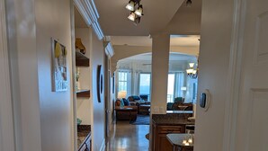 A spacious hallway with a kitchen area, a dining area, and a living room. - Top Floor Legacy Penthouse / Stunning Gulf Views / Walk to Beach, Pools & more! (Gulfport)