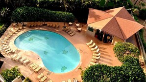 Une piscine avec des chaises longues et un espace de détente abrité.