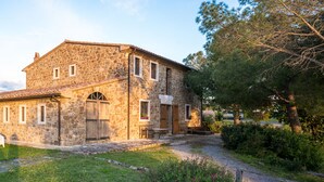 A stone building with a tiled roof, a paved pathway, and outdoor seating. - Tuscan Stone Farmhouse for 16 guests, amazing view, vineyards and olive trees (Manciano)