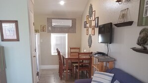 Una sala de estar con sofá, televisor y comedor con sillas y mesa.