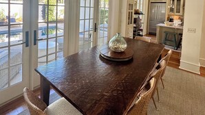 A spacious dining area with a large wooden table, wicker chairs, and a glass vase centerpiece.