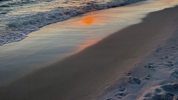 A beach with a sunset over the ocean.